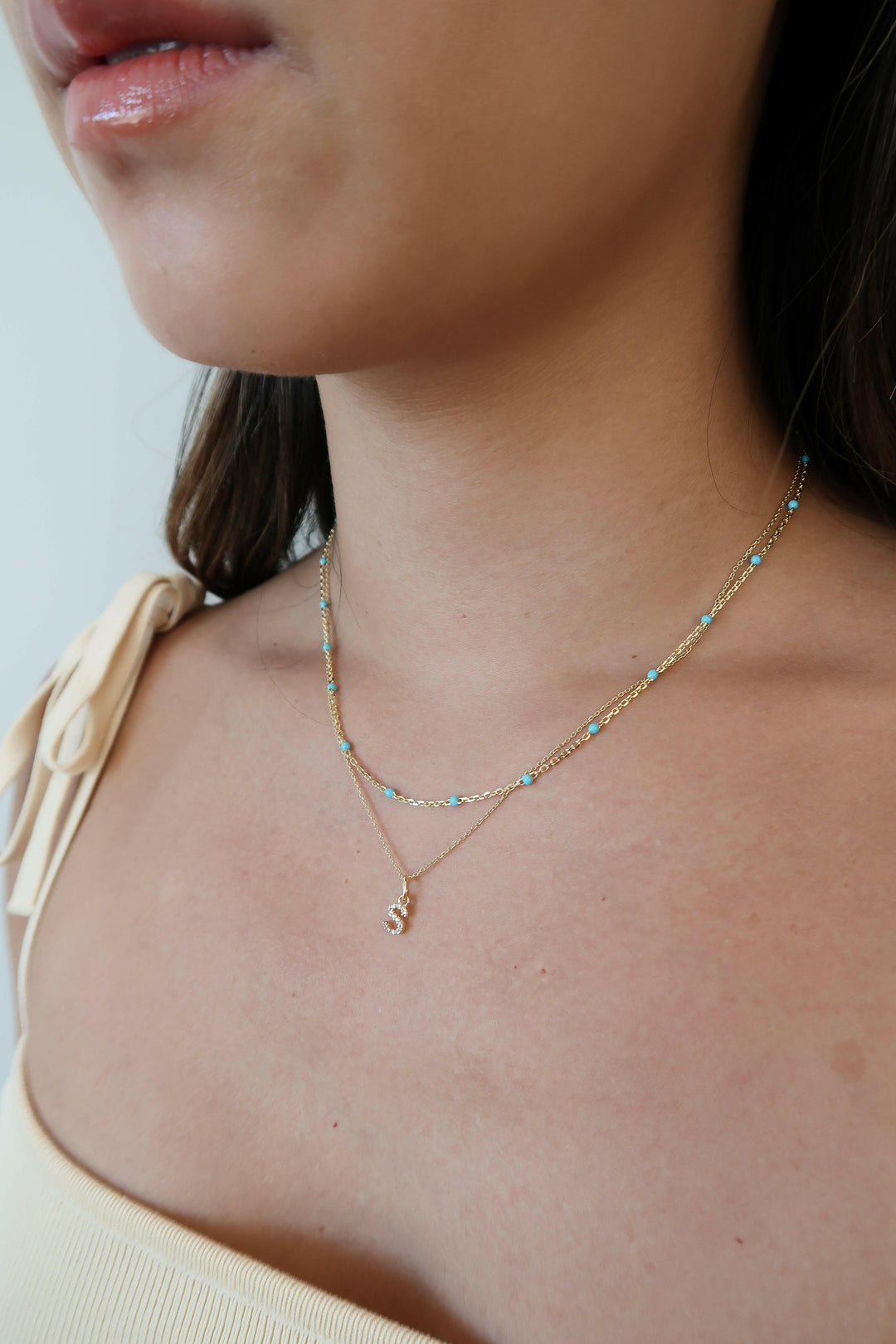 sparkling letter necklace layered with turquoise beaded necklace